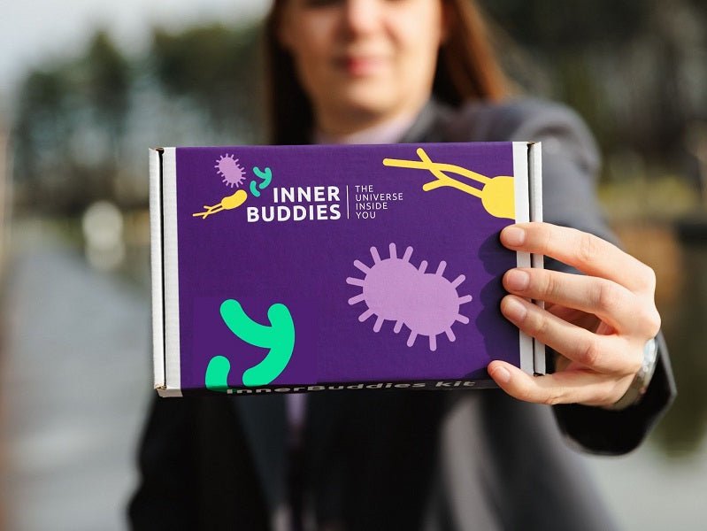 Person holding Inner Buddies gut microbiome test subscription box with microbes design