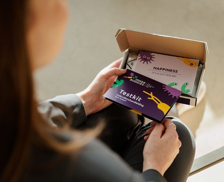 Person holding an open box with gut microbiome test subscription kit and instructions inside