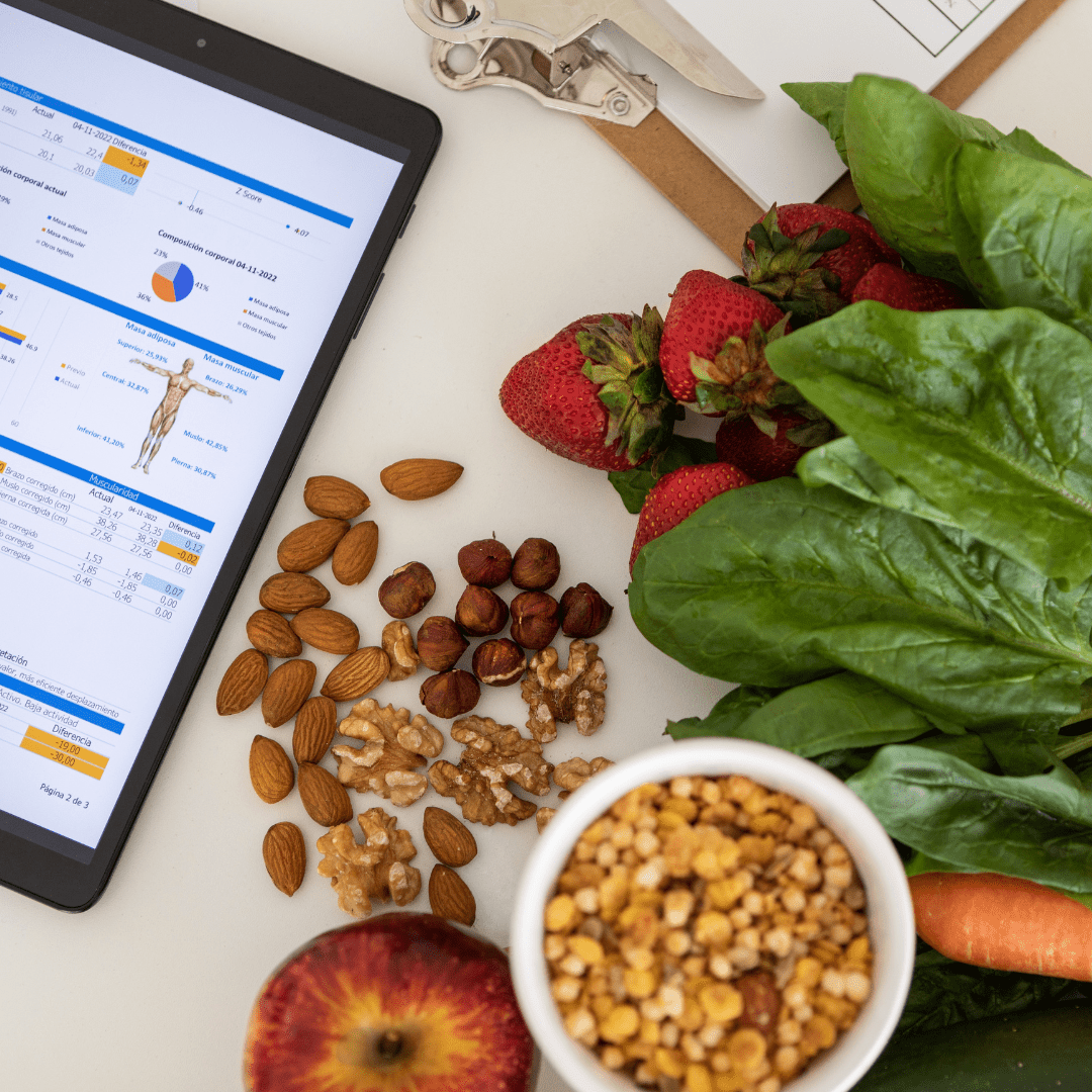 Tablet displaying health data with fresh strawberries, spinach, nuts, apple, and bowl of grains for personalised nutrition advice